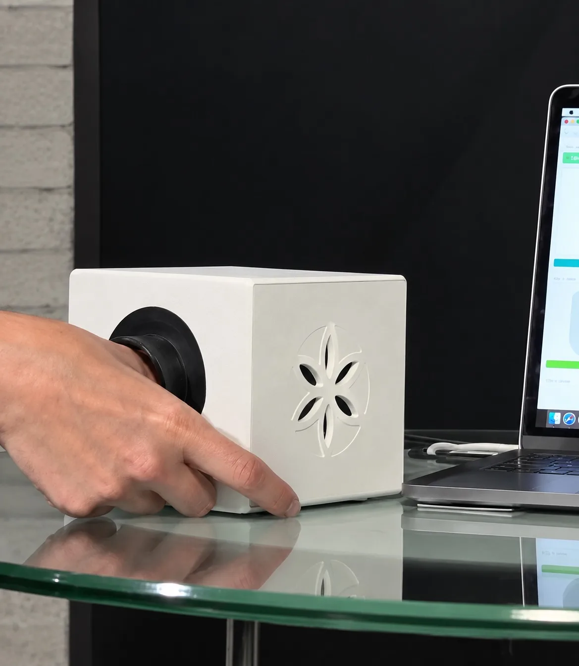 A hand at the Bio-Well scanner beside a laptop showing the fingertip scan screen